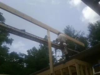 Carpenter setting a ridge beam over a new addition frame — Ice Dam Removal by Roofing Brothers in Mount Ayr
