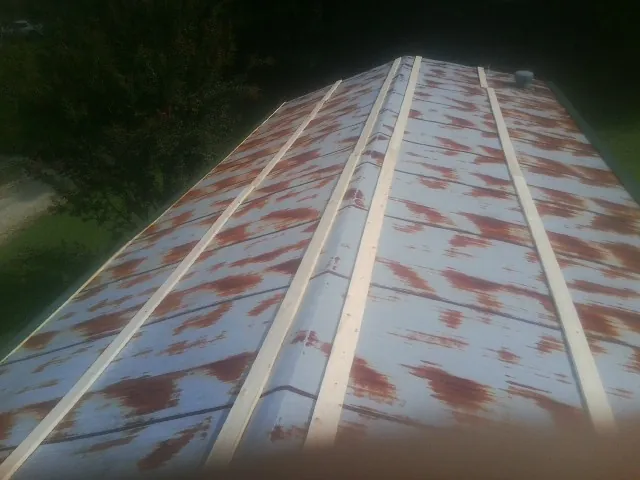 Rusted metal roof panels with new wood purlins before replacement — Storm Damage Roof Repair in Mount Ayr by Roofing Brothers