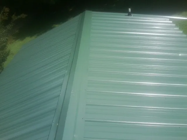New green metal panels meeting at the ridge of a roof — Flat Roof Repair work by our crew in Mount Ayr