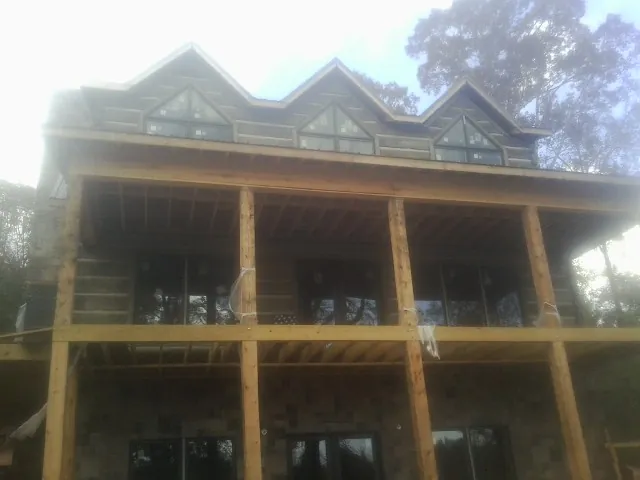Dormers and porch framing on a large log home under construction — Roof Coating work by our crew in Mount Ayr