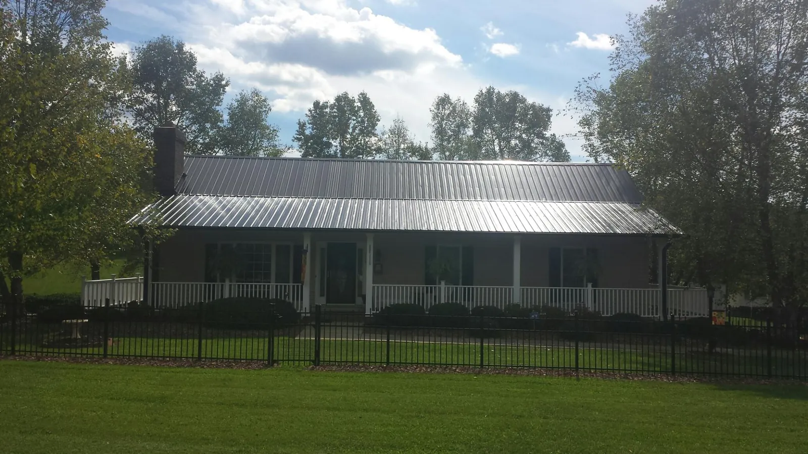 Gray metal roof on a brick ranch with a full width front porch in Mount Ayr