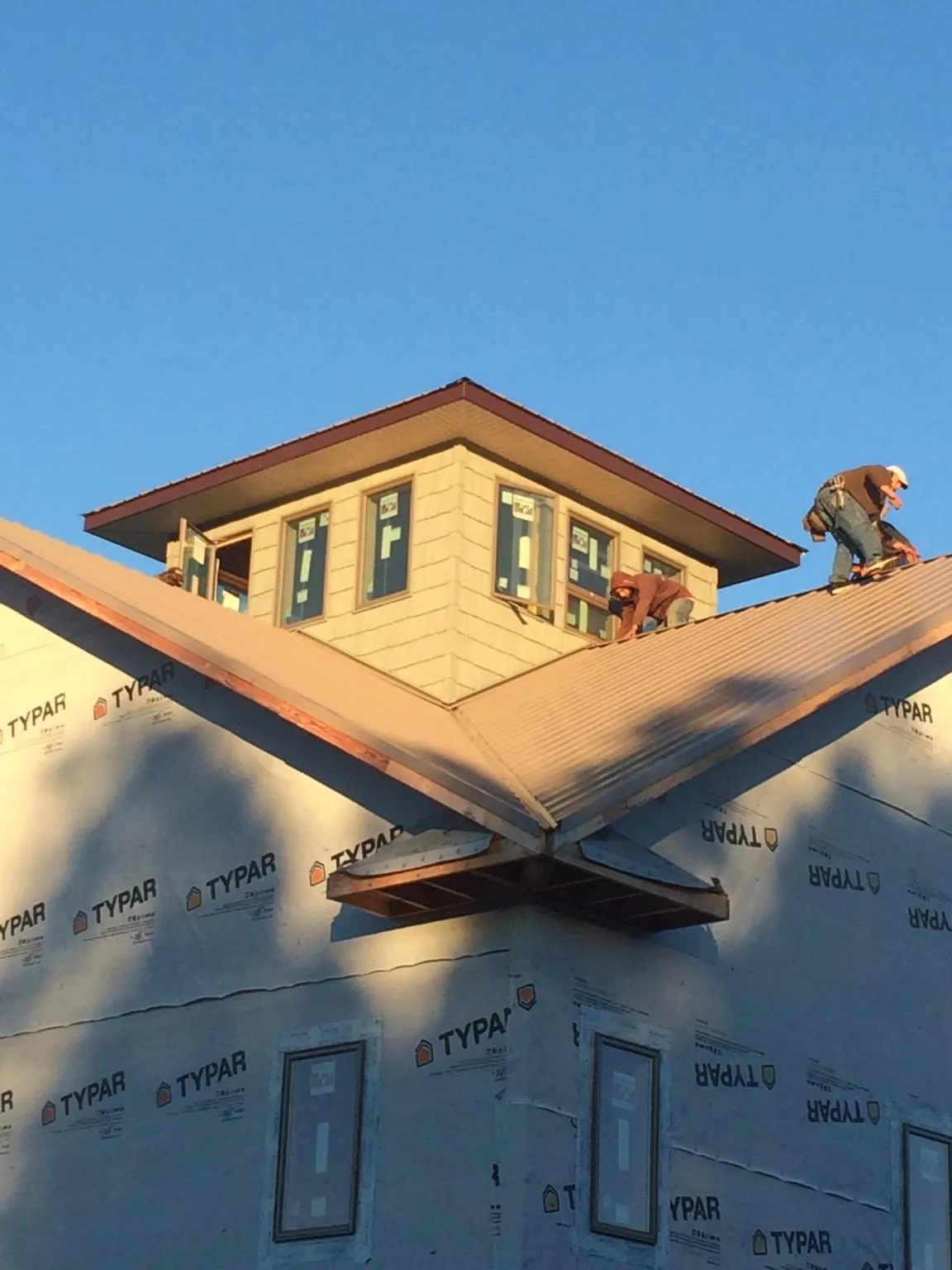 Roofers working around a rooftop cupola on a new metal roof at sunset — Roof Waterproofing in Mount Ayr by Roofing Brothers